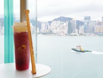 Close-up of drink on table in city against sky