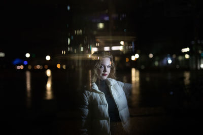 Portrait of woman standing in city at night