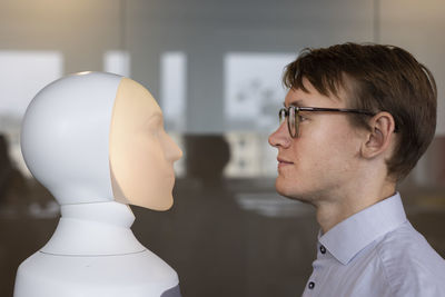 Young man looking at robot voice assistant