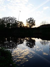 Reflection of silhouette trees in lake against sky