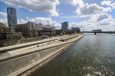 Bridge over river by buildings in city against sky