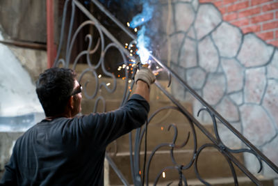 Man in safety glasses is welding metal of staircase. welding work on metal. blurred background.
