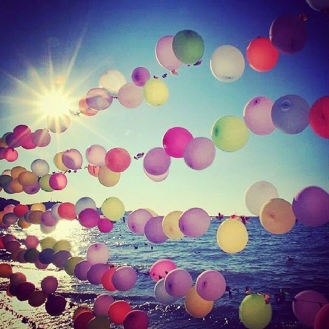 multi colored, balloon, sky, lens flare, low angle view, colorful, blue, sun, hot air balloon, celebration, circle, abundance, decoration, clear sky, sunlight, large group of objects, outdoors, variation, mid-air, nature