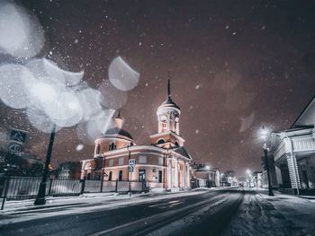 Road amidst buildings in city during winter at night