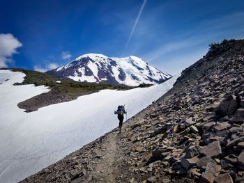 Man walking on snowcapped mountain against sky