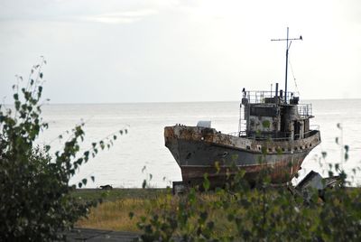 Abandoned ship moored in sea against sky