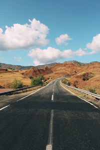 Empty road along landscape against sky