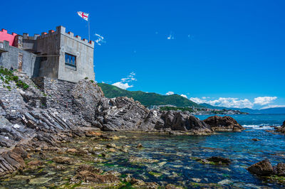 Scenic view of sea and buildings against blue sky