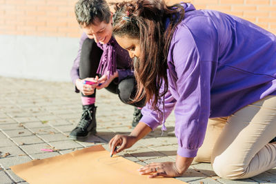 Cheerful females writing on poster outdoors