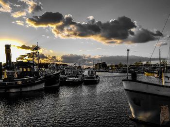 Boats moored at harbor against sky during sunset