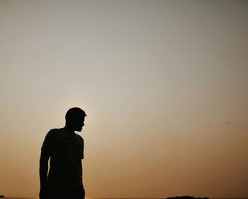 Silhouette man standing against clear sky during sunset