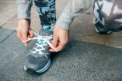 Low section of man tying shoelace