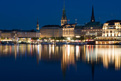 Illuminated city centre of hamburg with alster river in front