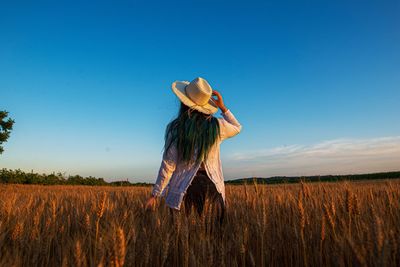 Rear view of woman standing on field against clear sky