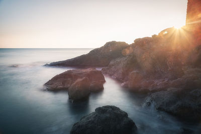 Rock formations in sea against sky