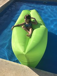 High angle view of girl sitting on pool raft at swimming pool