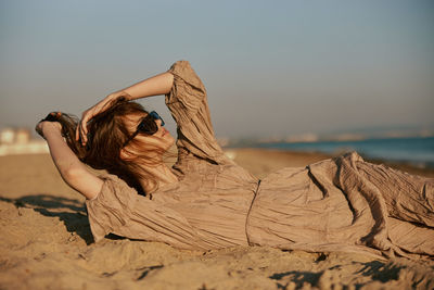 Rear view of woman sitting on sand at beach