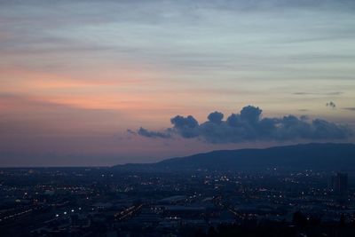 Aerial view of illuminated city against sky at sunset