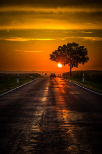 Road amidst trees against sky during sunset