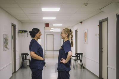 Side view of smiling female medical staff talking with each other while standing at healthcare center