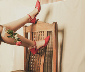 Legs of woman in red red upside down  against wall