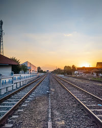 Surface level of railroad tracks against sky during sunset