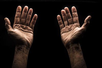 Person gesturing hands against black background