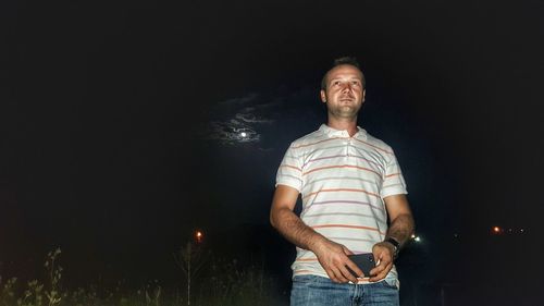 Low angle view of man looking away while standing against sky at night