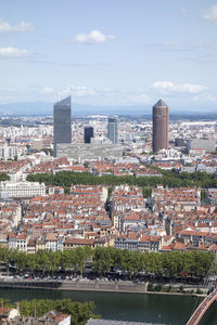 Cityscape by river against sky