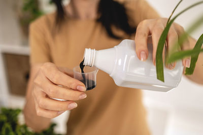 Midsection of woman holding bottle