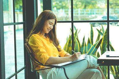 Young woman using phone while sitting on table