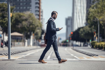 Male professional using mobile phone while walking in city