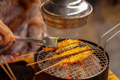 Close-up of person preparing food on barbecue grill