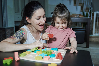 Happy girl playing with people sitting in kitchen