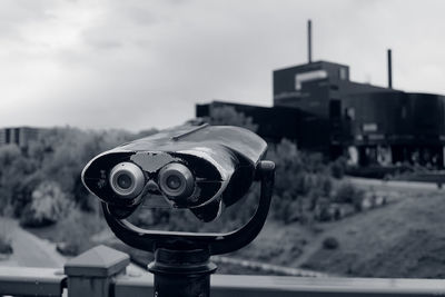 Close-up of coin-operated binoculars against cityscape