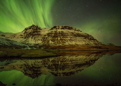 Scenic view of lake and mountains against sky at night