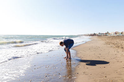 Blond guy tourist in jeans enjoying the beach and the sea