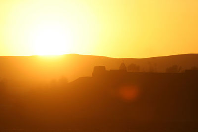 Scenic view of silhouette landscape against orange sky