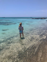 Rear view of woman standing at beach