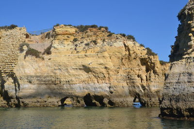 Panoramic view of rocks and sea against clear blue sky