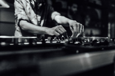 Dj is playing music in a nightclub. you can see his hands mixing music with his dj gear