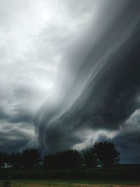 Low angle view of storm clouds over field