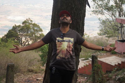 Portrait of young man standing against trees