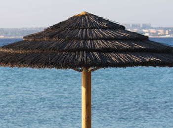 Close-up of wet umbrella on beach against clear sky