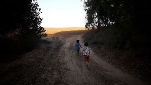 Rear view of people walking on road against sky