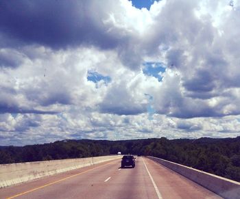 Car on road against cloudy sky