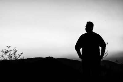 Rear view of silhouette man standing on field against sky
