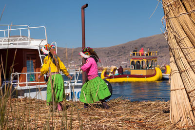 People sitting on boat against clear sky