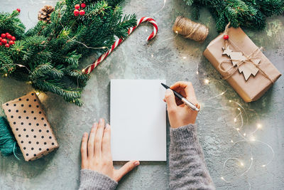 Cropped image of woman hand writing on notebook with christmas ornaments