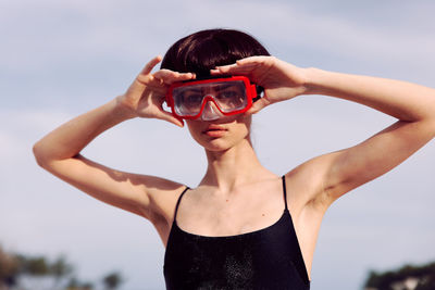 Portrait of young woman wearing sunglasses while standing against sky